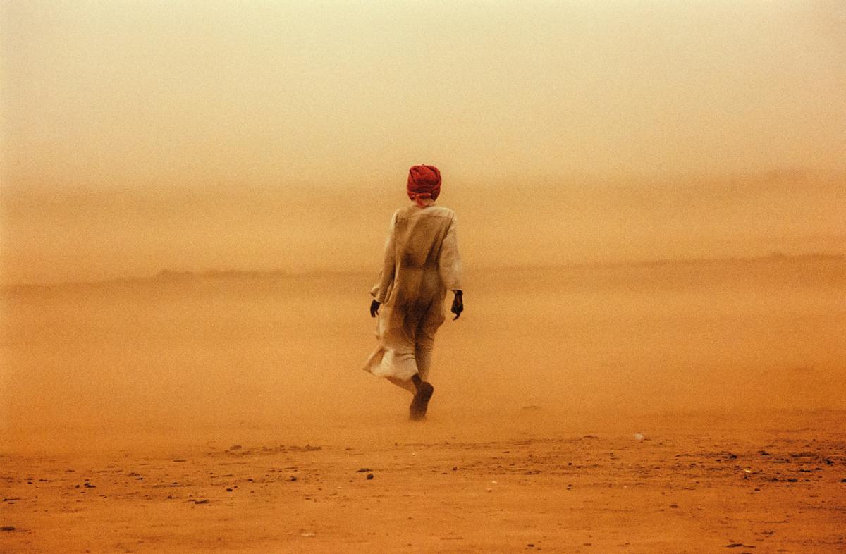 A comienzos de 2004, la tragedia de Darfur se agravaba a pasos agigantados. MSF envió a un equipo a esta calurosa región sudanesa. Después de compartir mesa y tés durante unos meses, me hice colega de uno de los responsables de la Policía de Tráfico de la ciudad. Nos entendíamos en un italiano horrible. En su vida de civil, era un astuto comerciante de animales. Un día tormentoso, lo acompañé al mercado de camellos. (Darfur, Sudán, 2004).