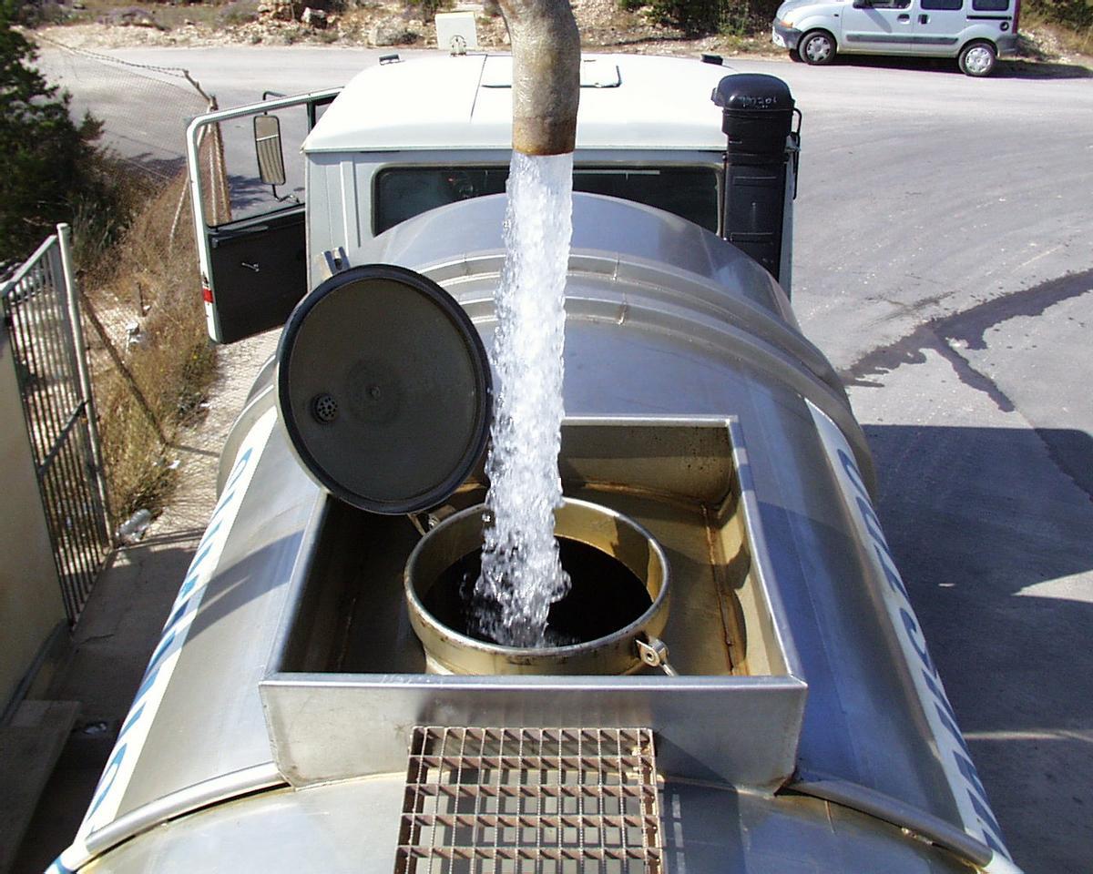 Un camión cuba, cargando agua potable de un pozo comercial en el campo