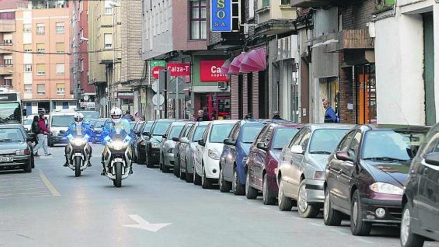 Dos mototistas de la Policía Local, patrullando por la calle Doce de Octubre, con aparcamiento de zona azul.