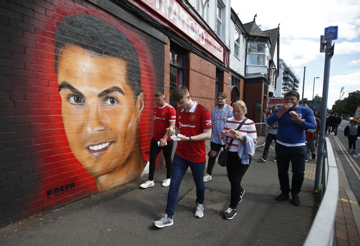 Aficionados del Manchester United camina ante un mural con la imagen de Cristiano Ronaldo