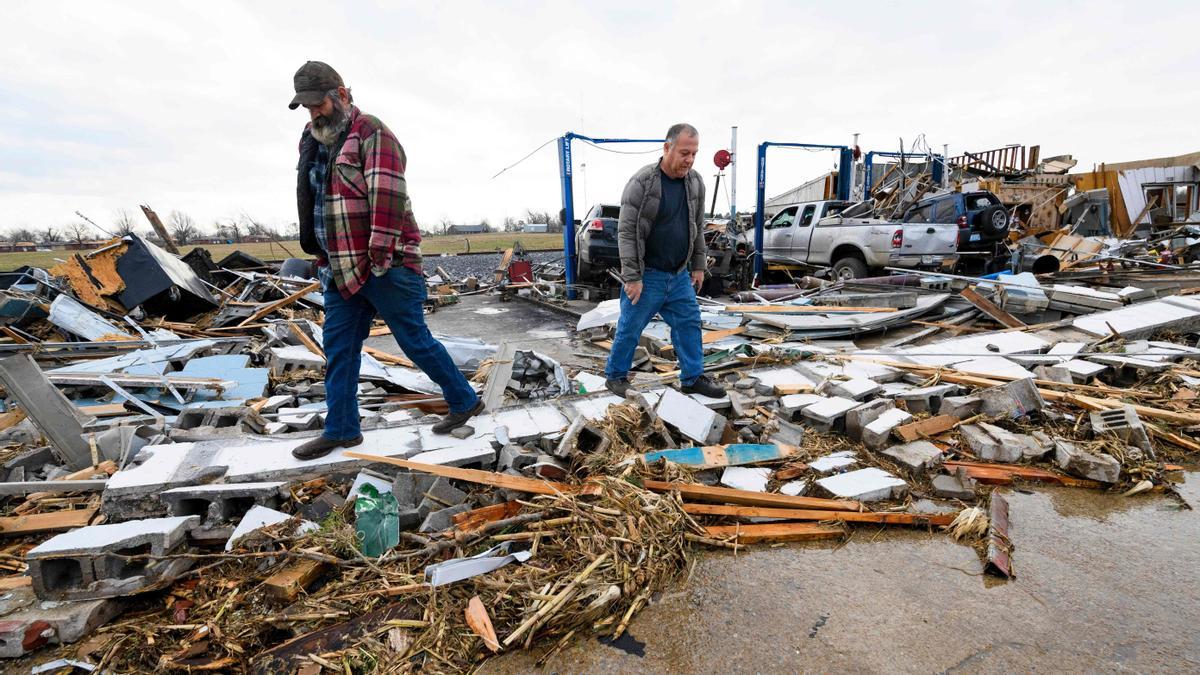 Martin Bolton (izquierda) y el dueño de la tienda Danny Wagner miran a través de los escombros del taller de reparación de automóviles de Wagner después de que fuera destruido por un tornado.