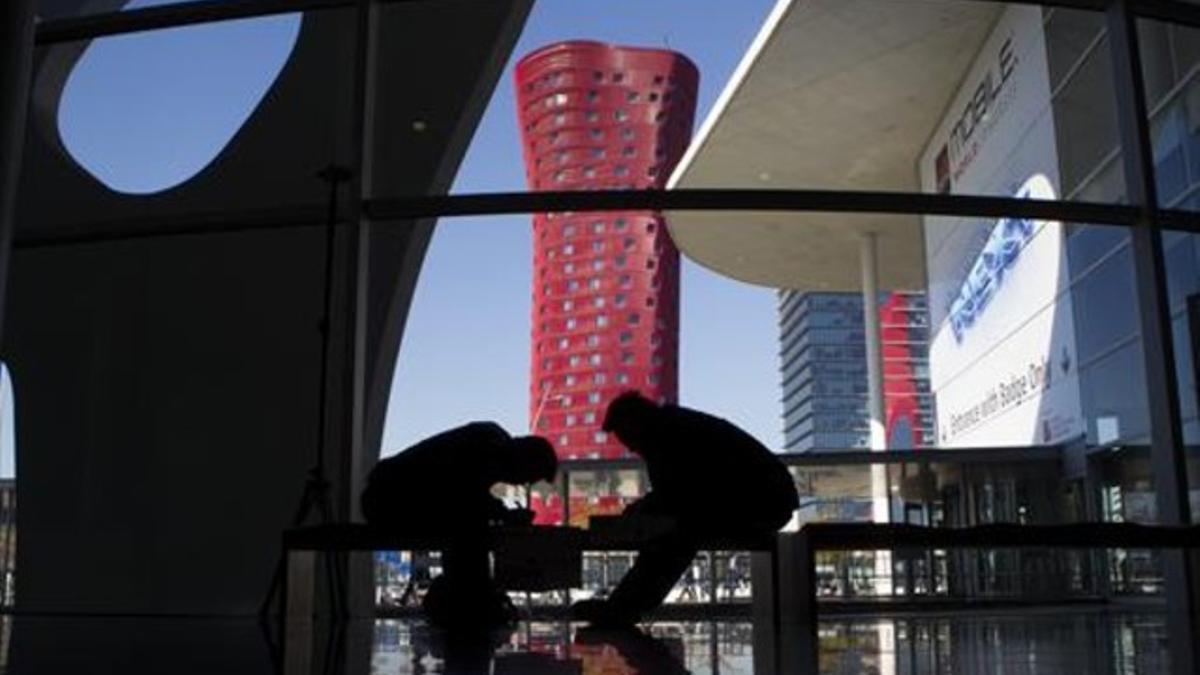 Asistentes al Mobile World Congress, en L'Hospitalet, con la torre del Hotel Porta Fira al fondo.