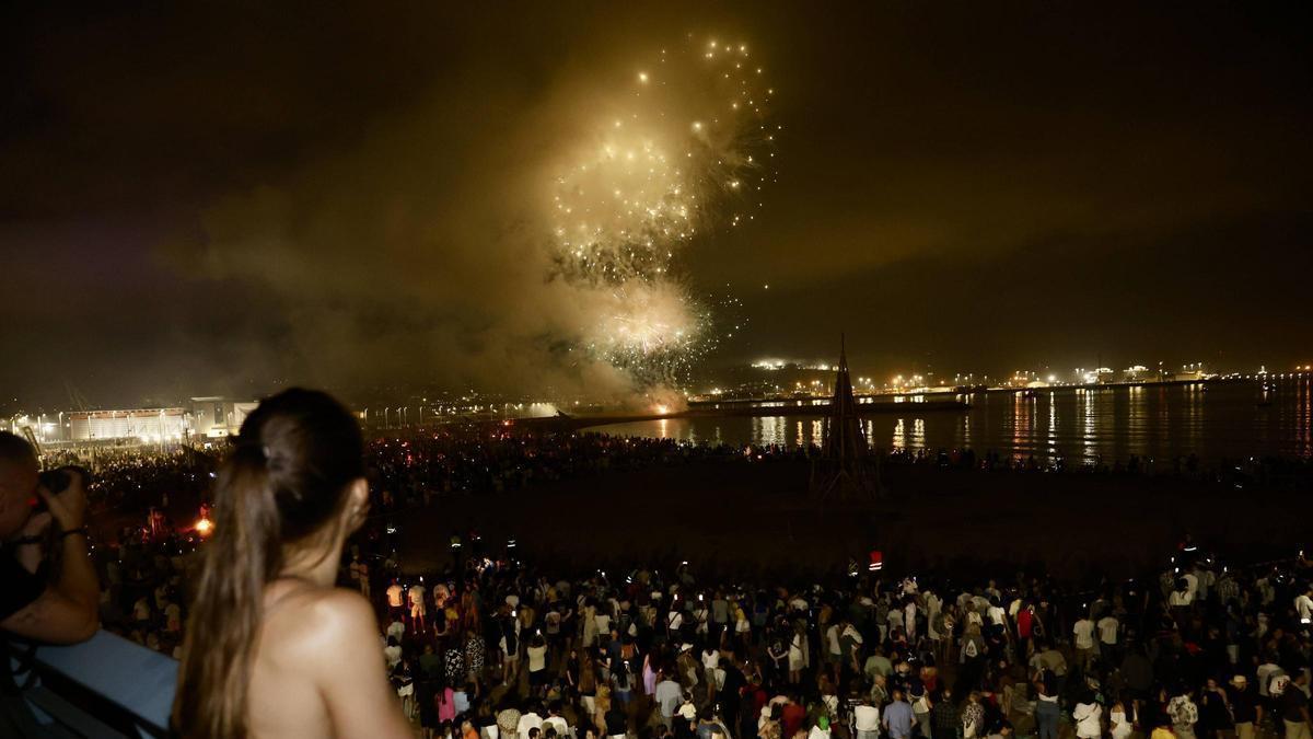 Una joven observa la hoguera de San Juan en la playa de Poniente.
