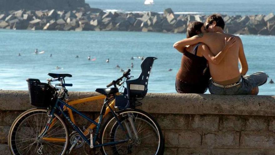 Una pareja se besa frente a una playa. // Efe