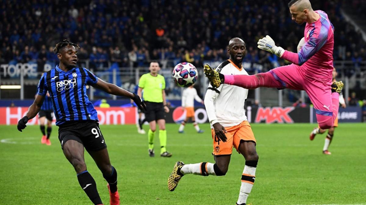 El portero del Valencia Jaume Domenech salta para parar el balón ante Duvan Zapata del Atalanta durante el partido de la UEFA Champions League entre el Atalanta Bergamo y el Valencia en el estadio San Siro en Milan.