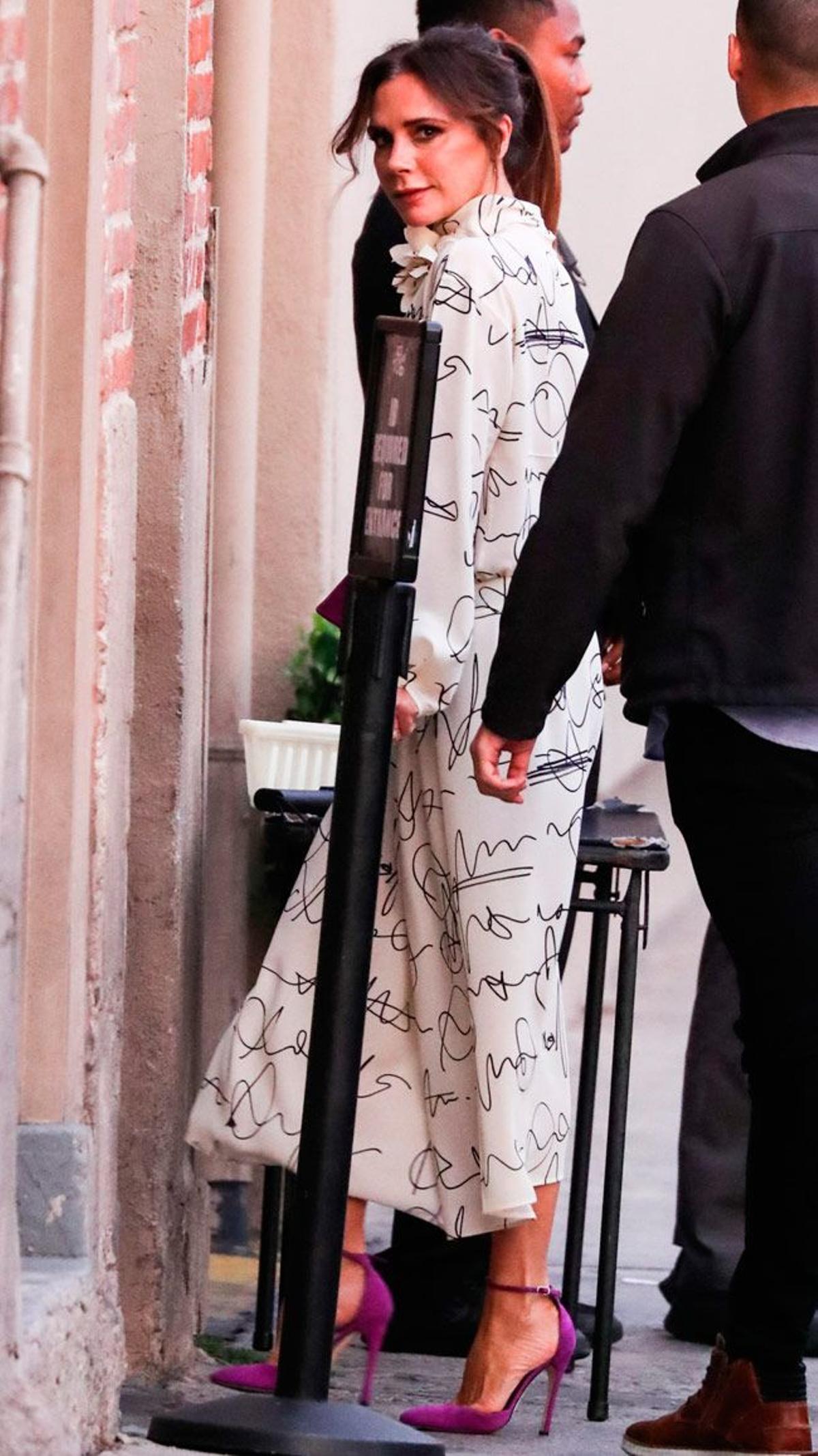Victoria Beckham con camisa y falda estampada y sandalias de tacón de su marca