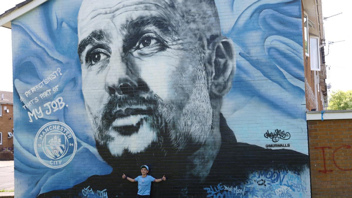 Un aficionado del City se fotografía ante un mural de Guardiola en Manchester.