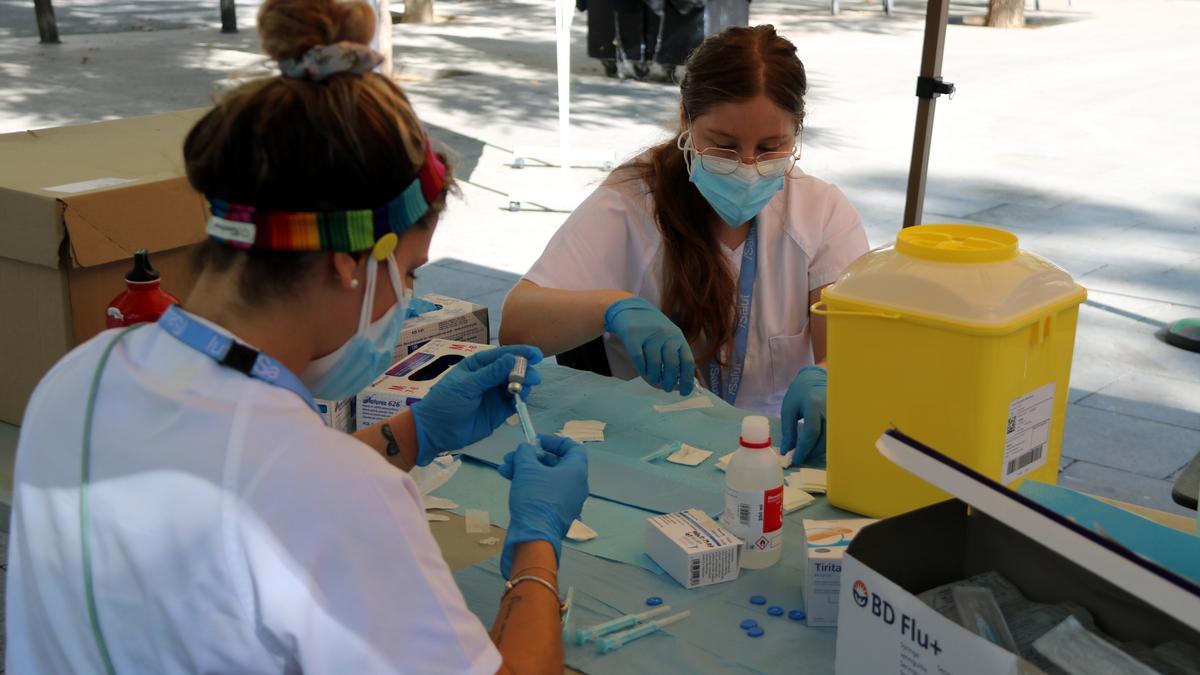 Imatge de dues infermeres preparant dosis de la vacuna al punt mòbil instal·lat a la plaça del Sortidor