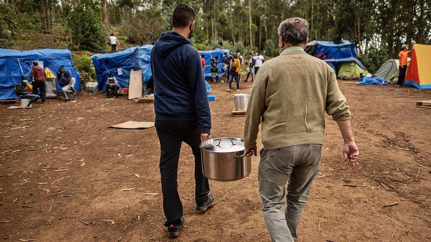 Dos ciudadanos llevan comida a migrantes cerca del campamento de Las Raíces.