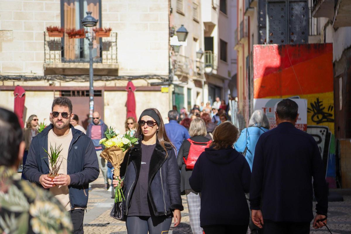 Trasiego de personas en el entorno de la plaza Alta, con flores compradas en el mercado.