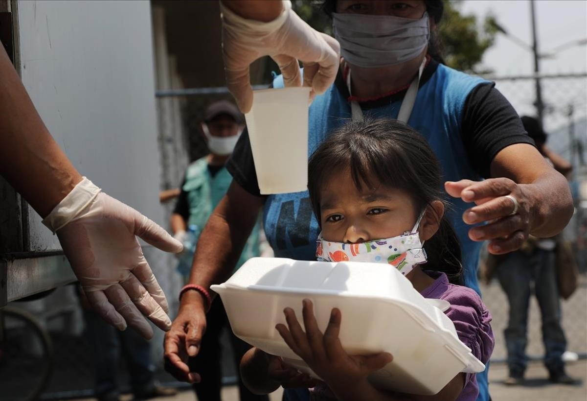 Un niño recibe una comida del programa de comedores móviles para personas que no han podido trabajar debido a la pandemia de COVID-19 frente al hospital de Iztapalapa.