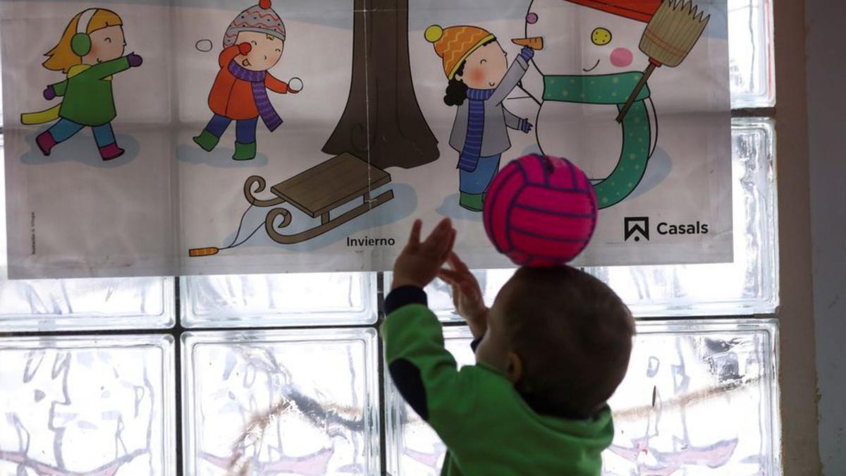 Un niño juega a la pelota frente a un gran dibujo en una escuela infantil.