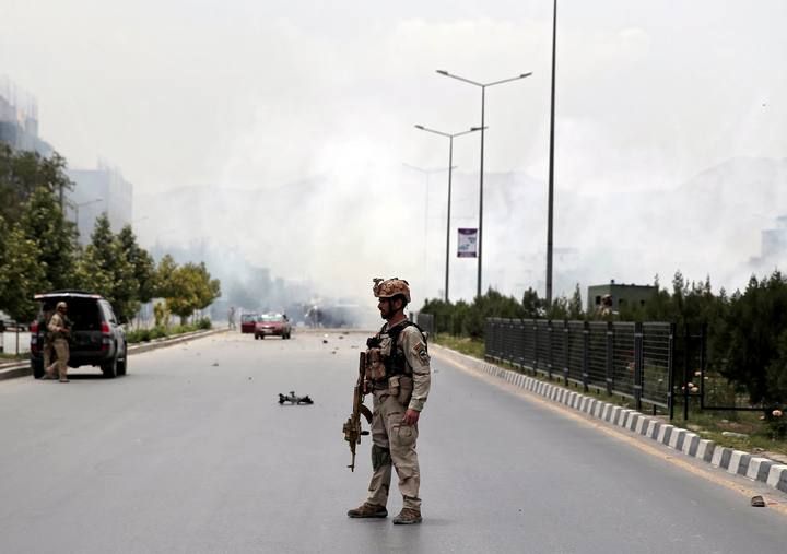 Member of Afghan security forces stands on a road at the site of an attack near the Afghan parliament in Kabul, Afghanistan
