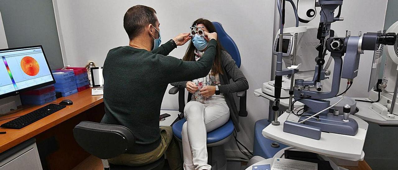 Andrés Martínez realizando una revisión ocular a una clienta en su óptica de Pontevedra.