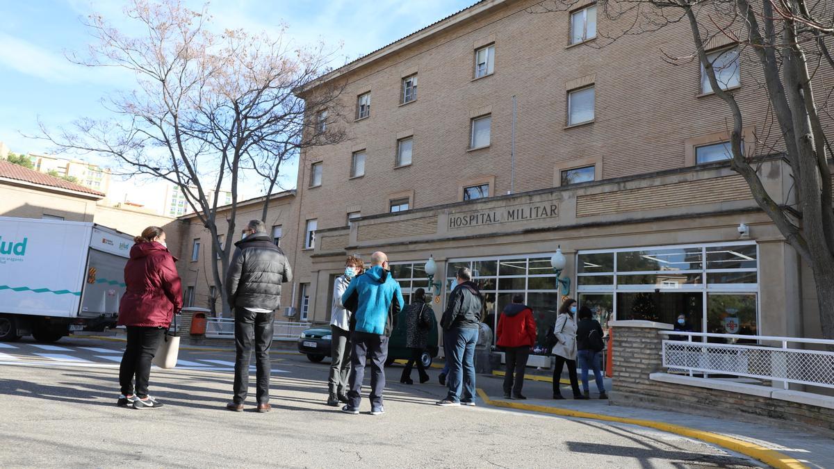 Varias personas hacen fila, este martes, a las puertas del hospital Militar de Zaragoza para ponerse la vacuna de refuerzo.