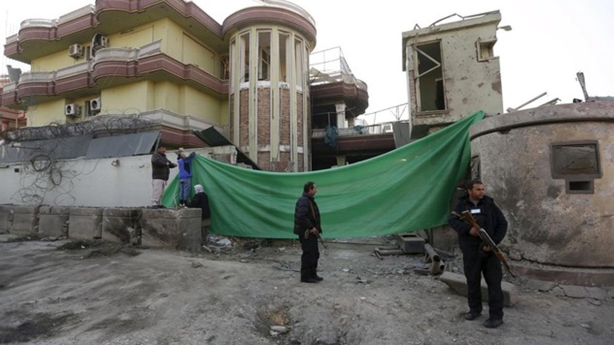 Afghan security personnel stand guard outside the guest house building after an attack near the Spanish embassy in Kabul, Afghanistan