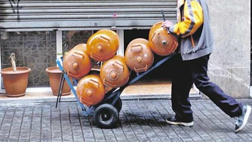 Un operario acarrea una pila de bombonas de butano por una calle de Palma.