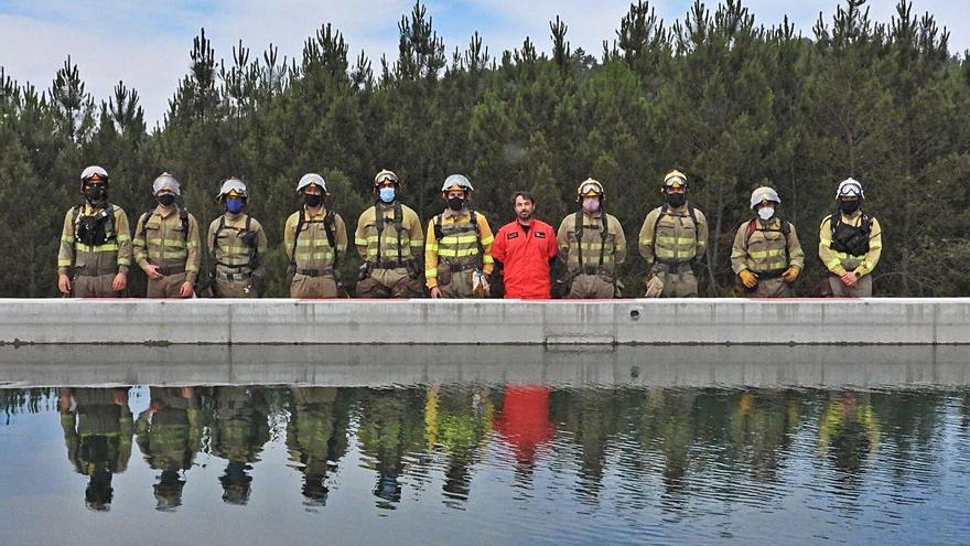 Bomberos forestales y un piloto, junto al punto de agua de Toén. // FERNANDO CASANOVA 