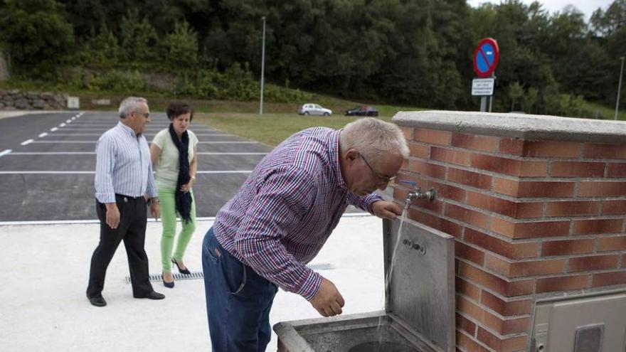 El edil José Manuel Álvarez bebe agua en el área de autocaravanas, con María y Vicente Fernández detrás.