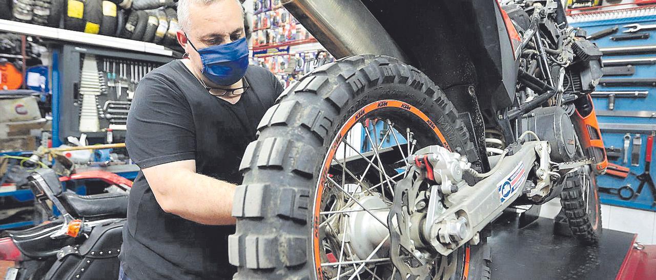 Un mecánico arregla una motocicleta en su taller.