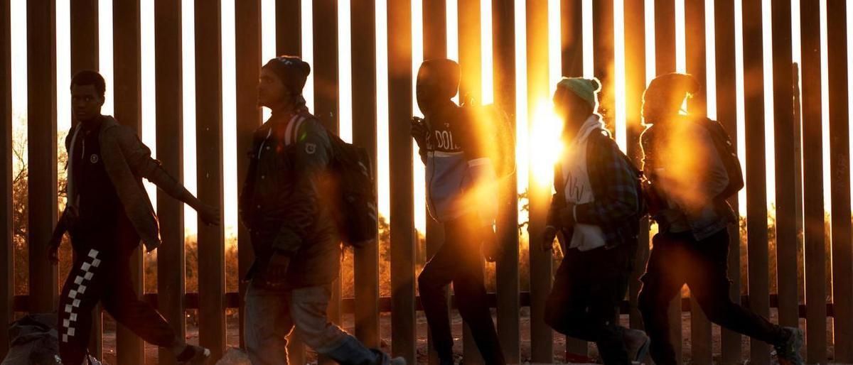 Un grupo de migrantes africanos camina junto al muro de la frontera de México y Estados Unidos, en la localidad de Lukeville.