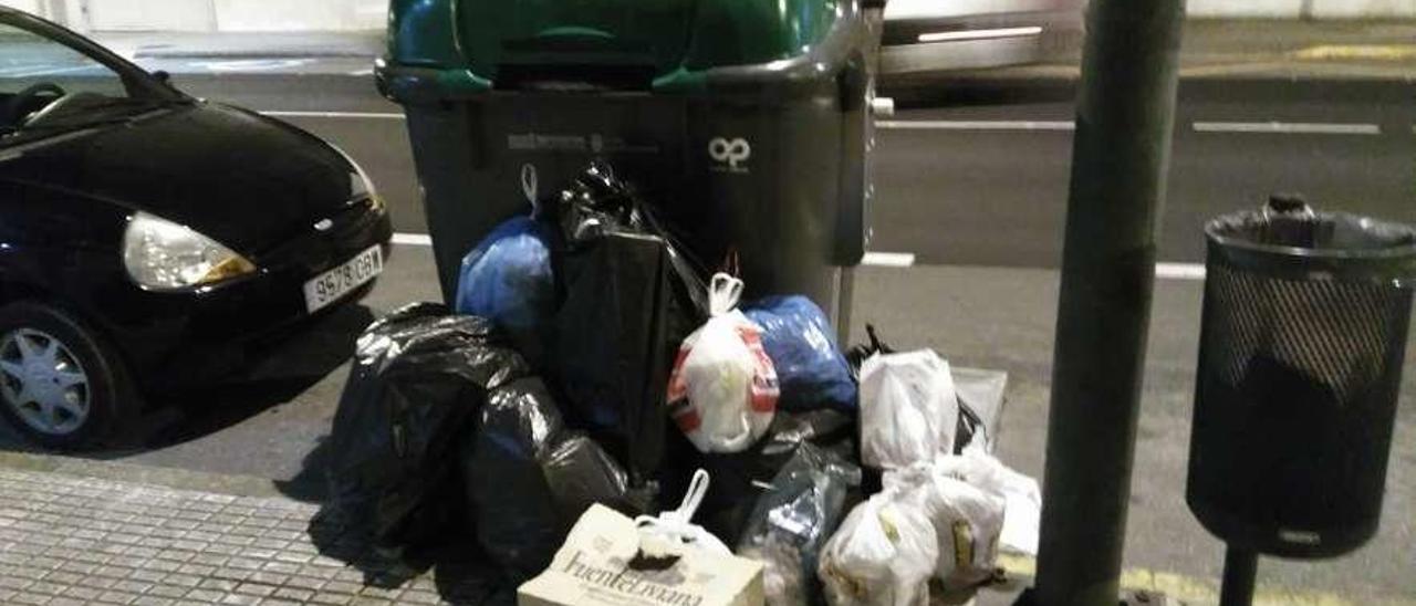 Contenedor en la avenida Benito Vigo, el domingo por la noche, rodeado de bolsas de basura.