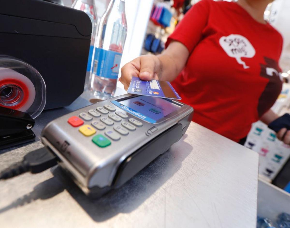Una mujer paga una compra con una tarjeta de crédito.   | // FERRÁN NADEU