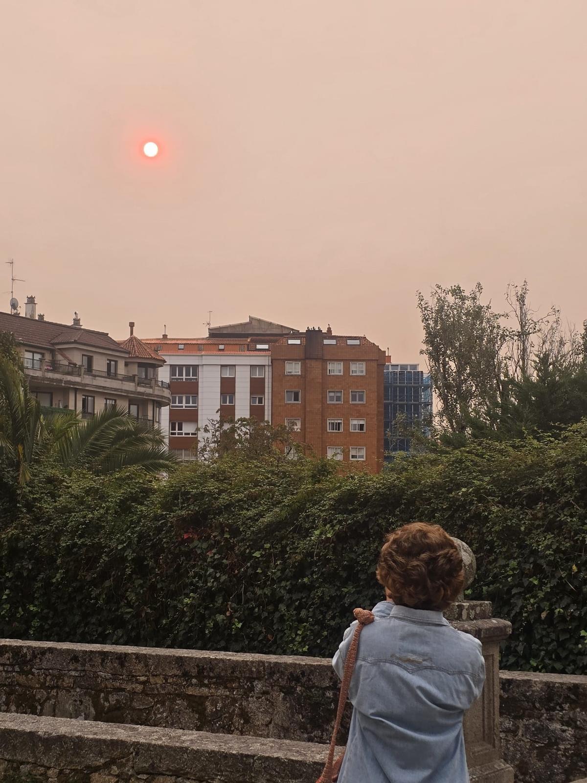 Una mujer fotografía el rojizo sol en Vilagarcía.