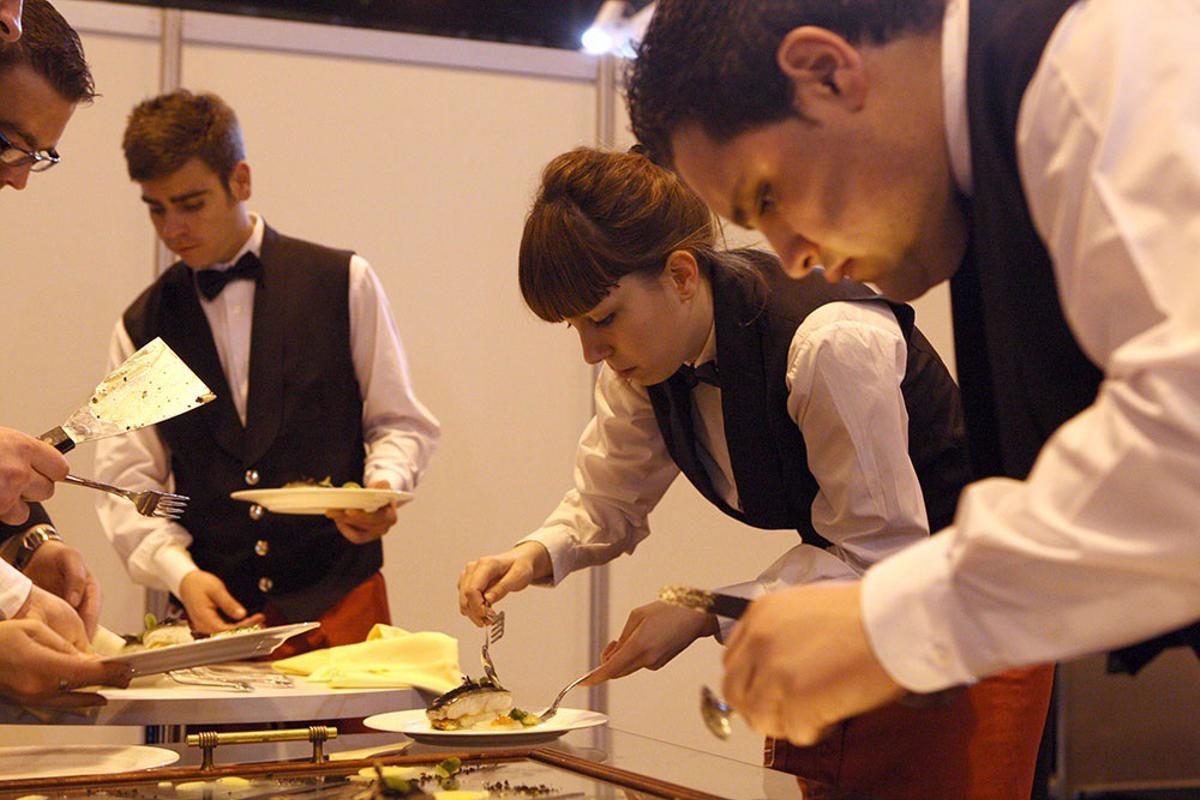 Jóveenes preparan platos para un evento.