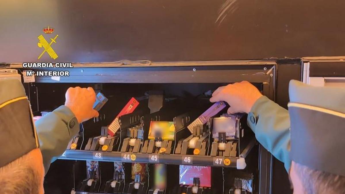 Dos agentes junto a una máquina de venta de vapers.