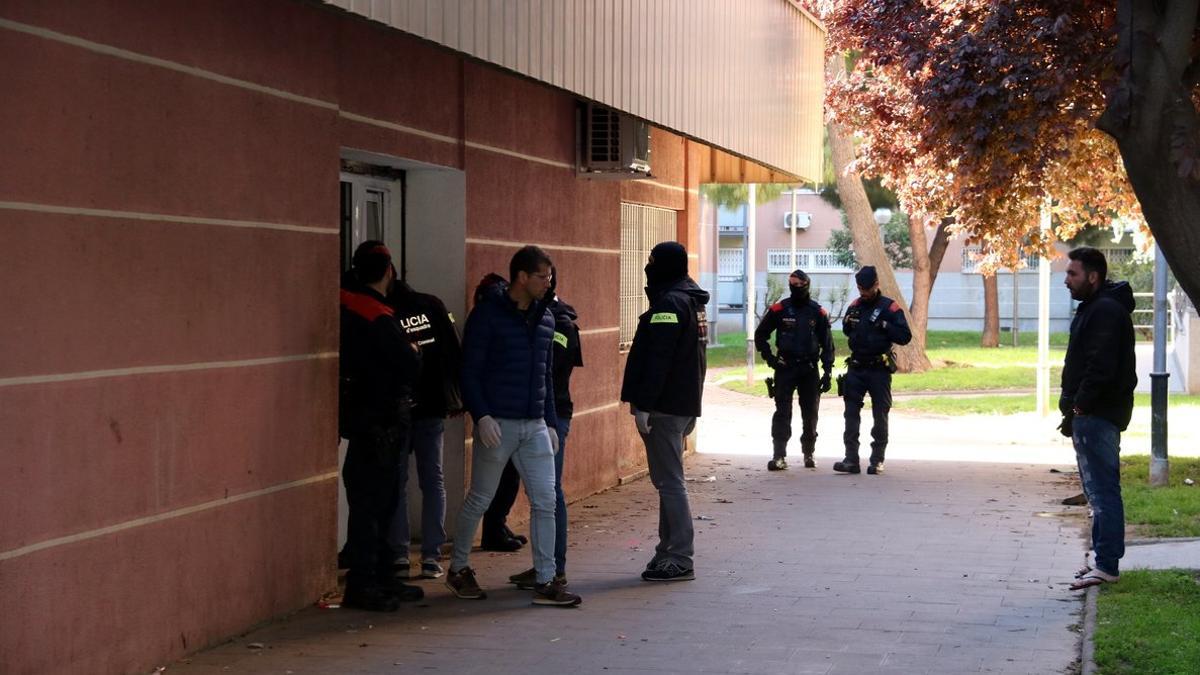 Agentes de los Mossos salen de uno de los edificios registrados, en el barrio de la Verneda.