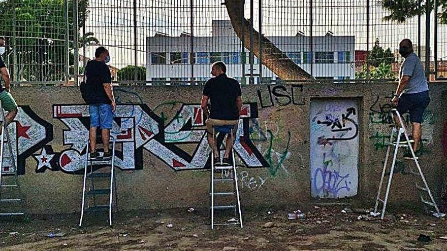 Varios aficionados subidos a una escalera viendo un partido.