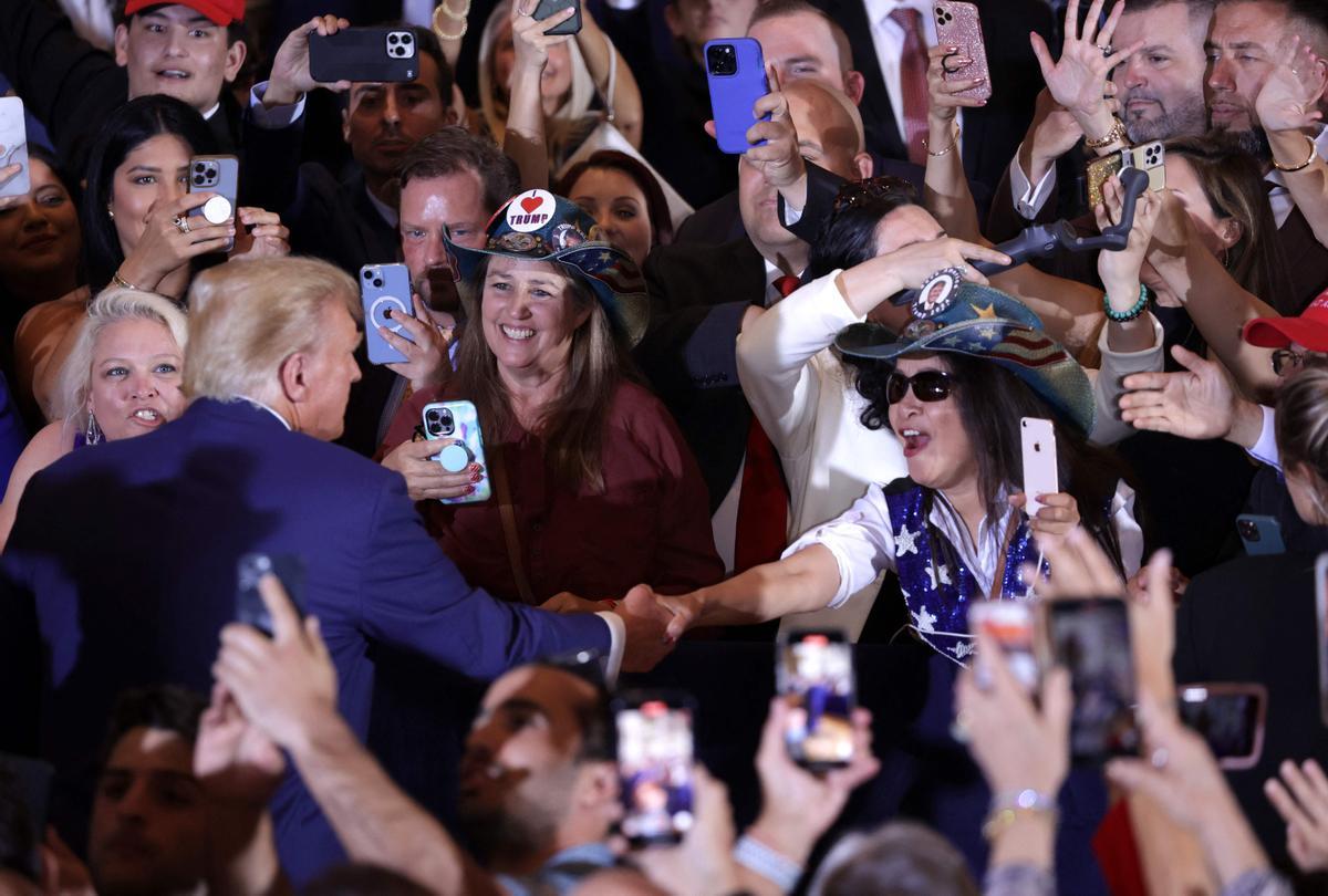 El ex presidente de los Estados Unidos, Donald Trump (L), saluda a sus seguidores durante un evento en Mar-a-Lago .