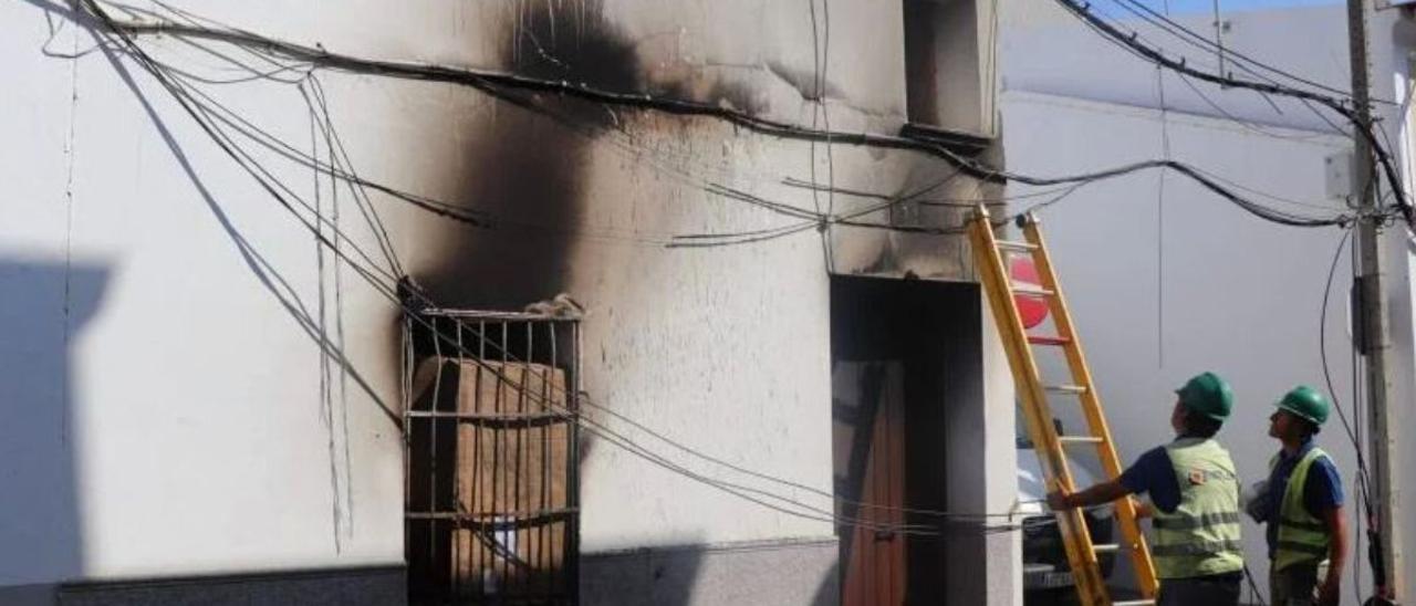 Dos operarios inspeccionan el estado de la instalación eléctrica tras el incendio.