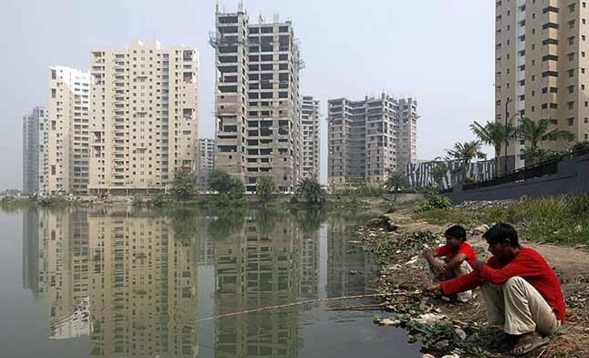 Dos homes pesquen en un estany a prop d’una urbanització en construcció a Kolkata (Índia).