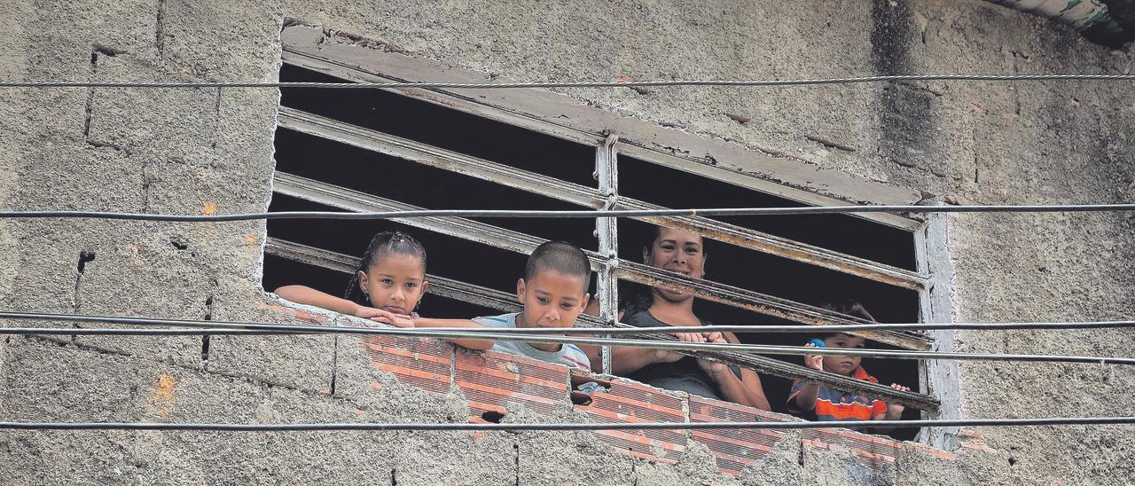 Una madre y sus hijos miran por una ventana en la barriada de infraviviendas de Petare en la que la crisis social y económicas de Venezuela se agudiza.