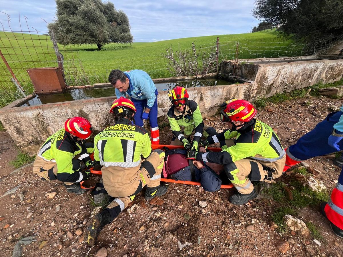Los bomberos evacúan a uno de los hombre rescatados este domingo en Palma del Río.