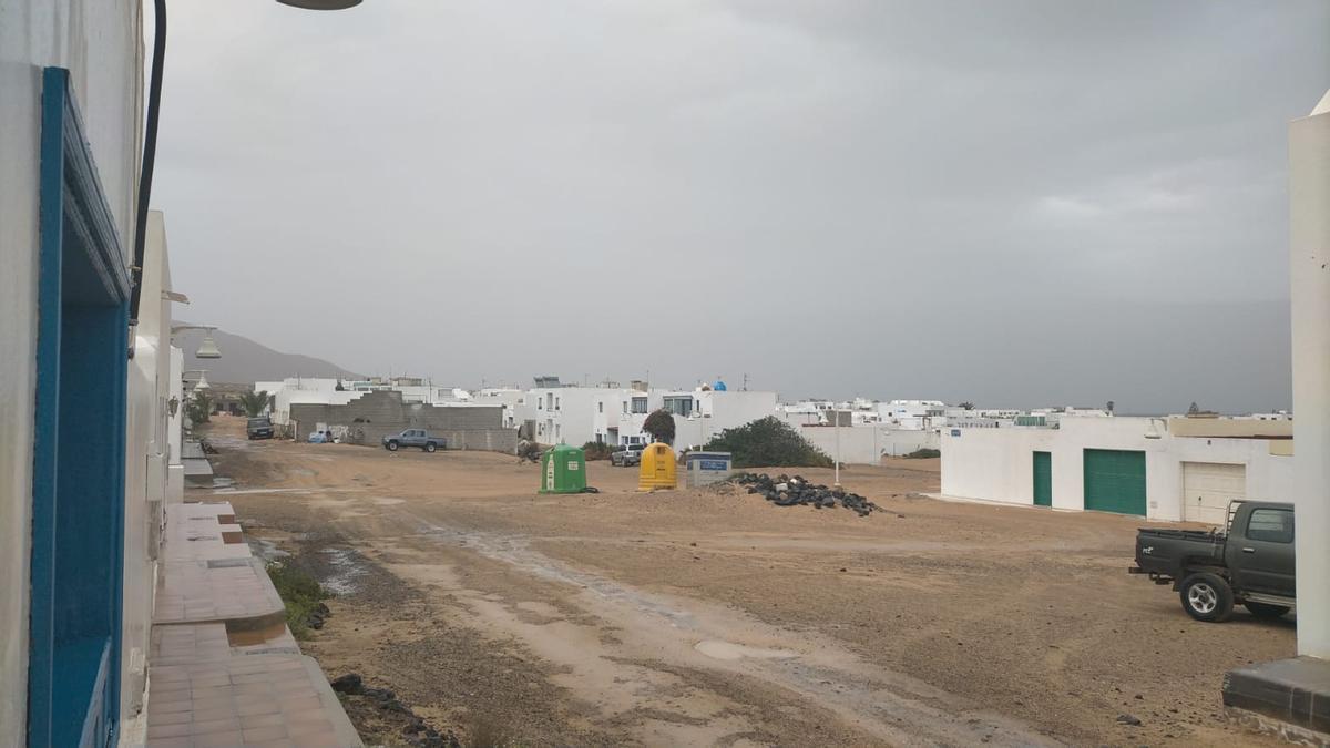 Calle de jable mojada por la lluvia débil este lunes en La Graciosa.