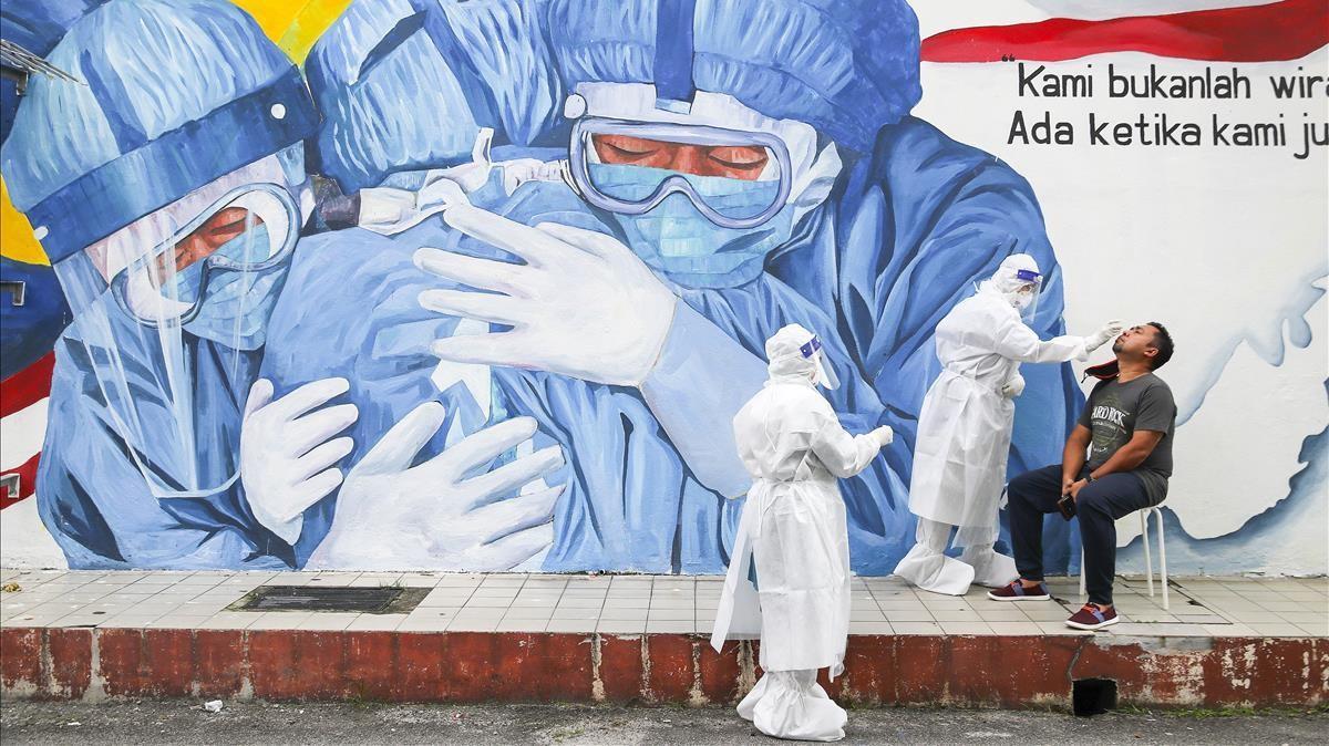 Recogida de muestras para test de covid en una clínica de Shah Alam, a las afueras de Kuala Lumpur (Malasia). De fondo, un mural dedicado a los sanitarios.