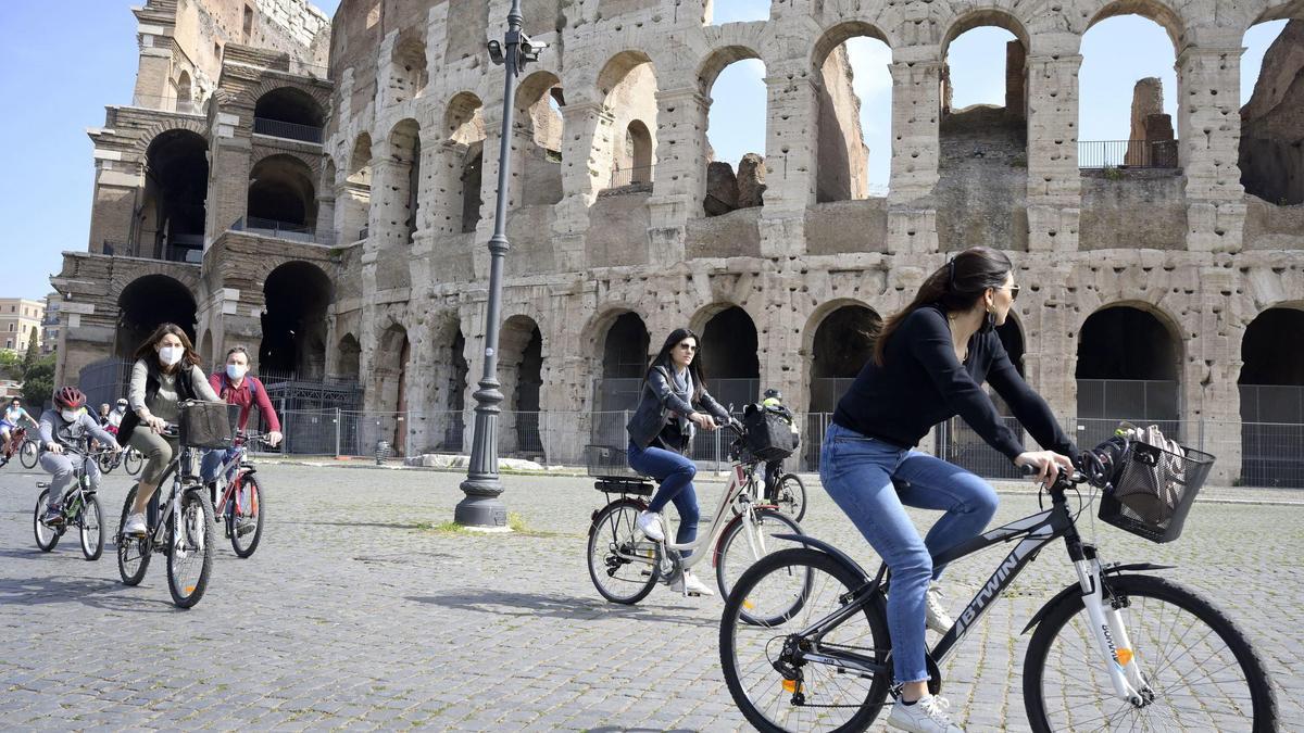 Unas chicas pasean en bicicleta por el Coliseo, en Roma.