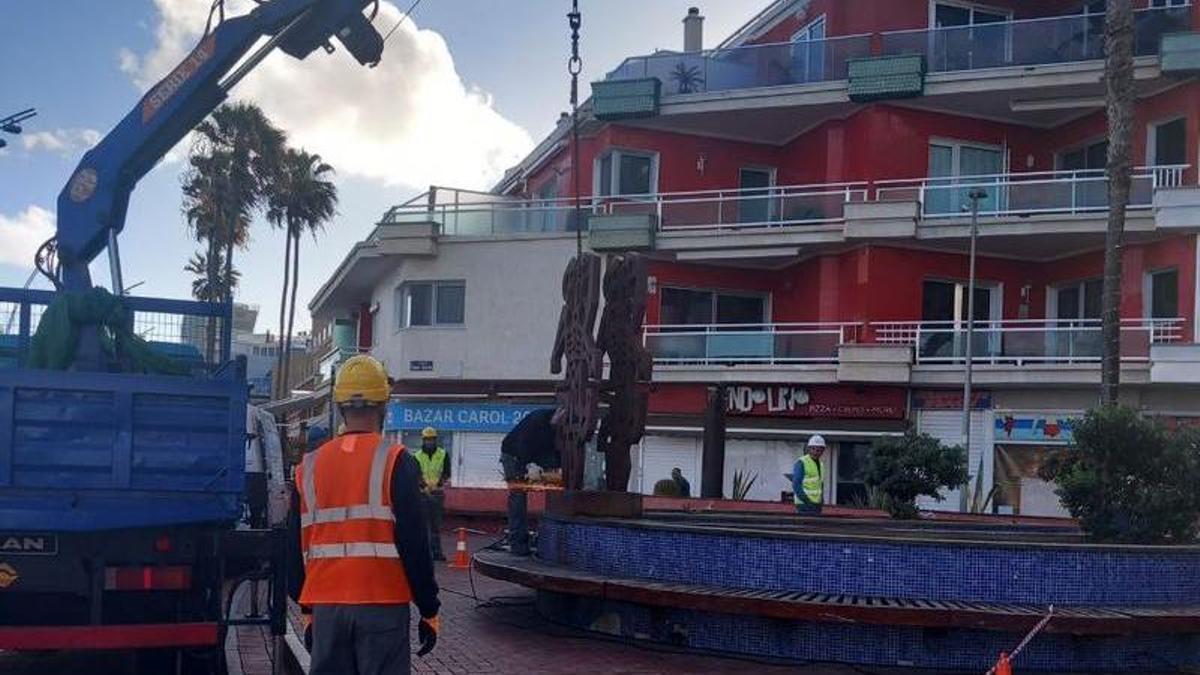 Operarios retiran la escultura 'La mujer y su sombra' para su reparación.