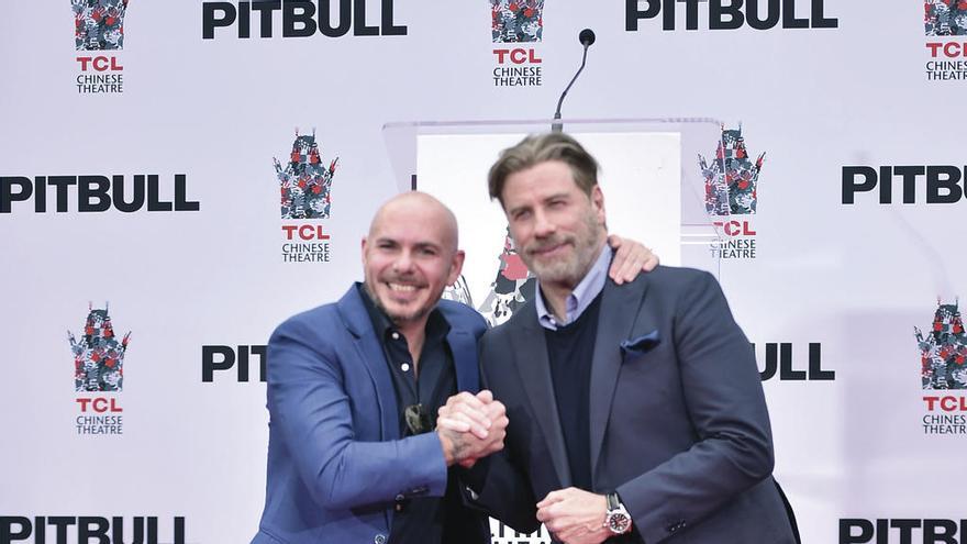 Pitbull y John Travolta. // AFP