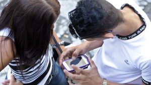 Dos jóvenes miran un teléfono móvil en La Habana.