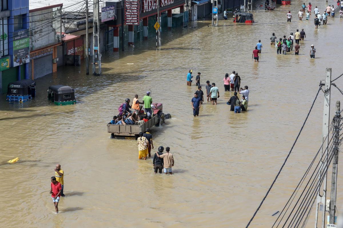 Residentes caminando entre las inundaciones por un barrio de Colombo. EFE/EPA/CHAMILA KARUNARATHNE