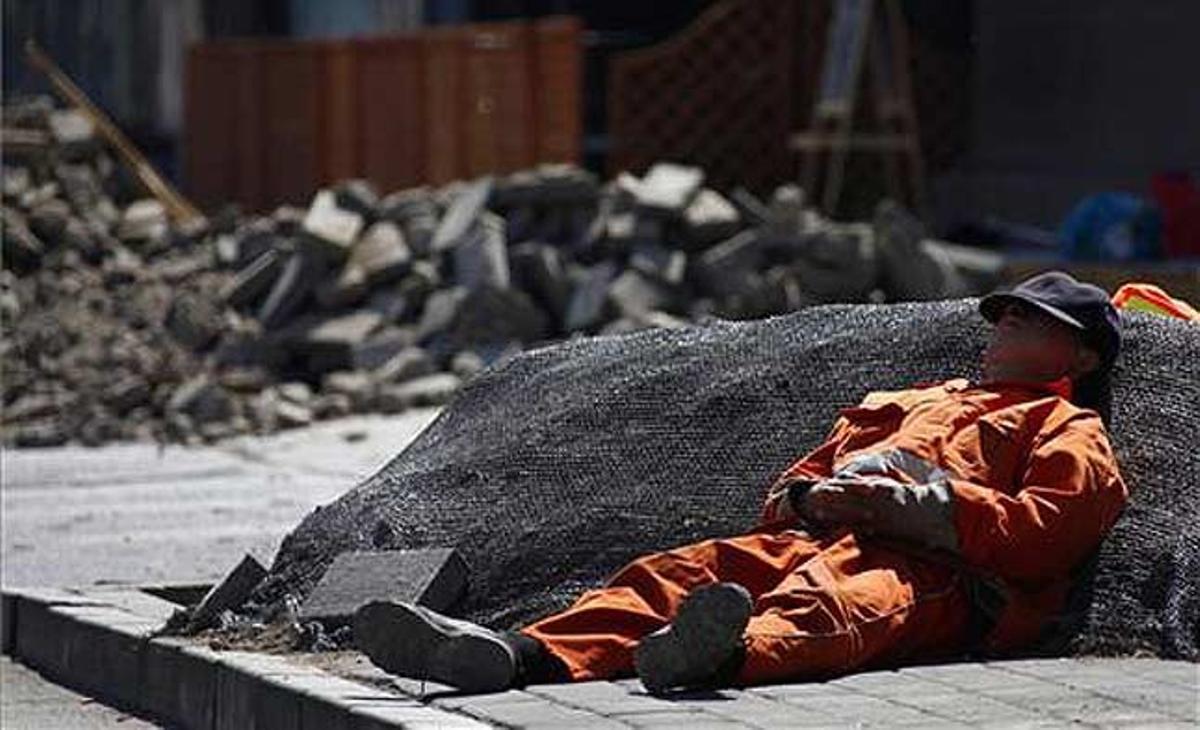 Un treballador descansa sobre un munt de runa, a Pequín (Xina)