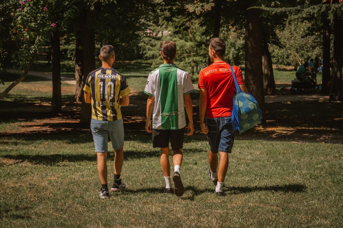 Santiago, Roberto y Pablo caminan vestidos con camisetas de fútbol por el Retiro.