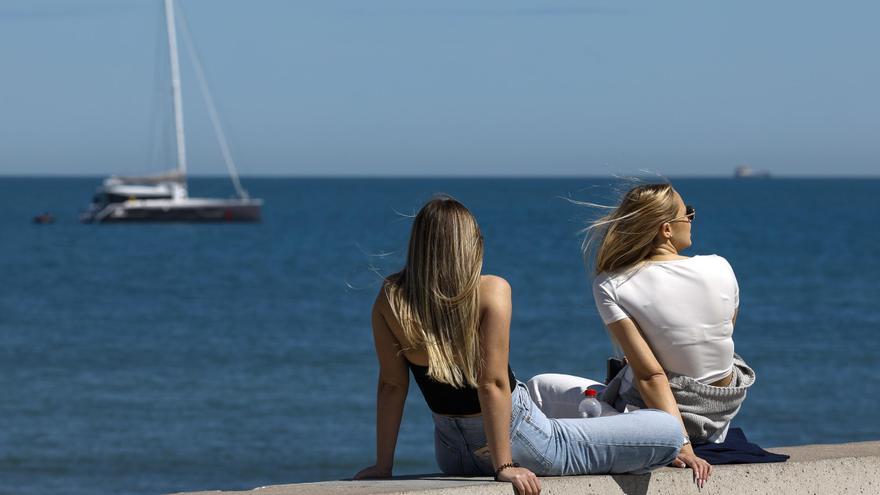 Dos chicas sentadas frente al mar.