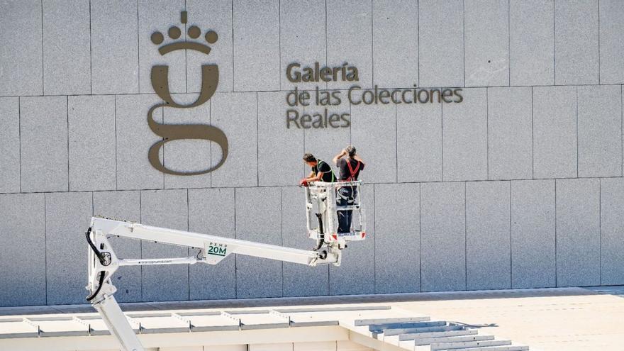 Dos operarios poniendo el indicador de La Galería en el edificio madrileño. | E. P.