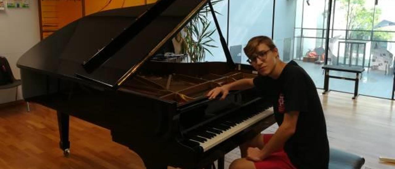 Ferran López Carrasquer posa junto a un piano en una sala de ensayos.