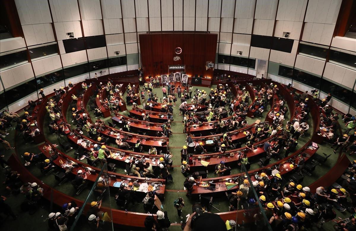 Cientos de manifestantes irrumpen en el Parlamento de Hong Kong (China), este lunes. Tras pasar más de cuatro horas intentando echar abajo la entrada del edificio con barras de acero, ladrillos o piedras, los manifestantes consiguieron acceder al interior.